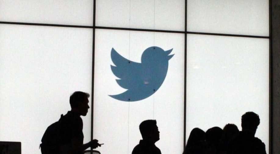 Siluet karyawan yang sedang melewati dinding berlogo burung biru Twitter